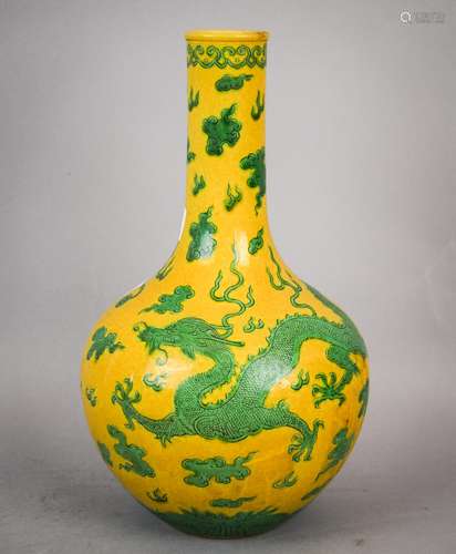 Porcelain vase. China. Early 20th century. Bottle form. Decoration of an engraved dragon celestial pearl and clouds in green on a mustard yellow ground. Ch'ien Lung mark on the base. 10