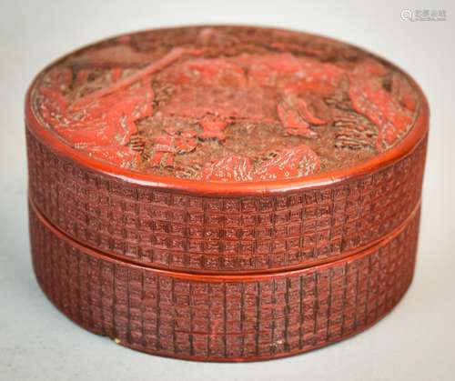 Cinnabar box. China. 18th/19th century. Round cylinder shape. Dark red colour. Top carved with figures in a landscape. Sides with a diapre pattern. 4-1/2