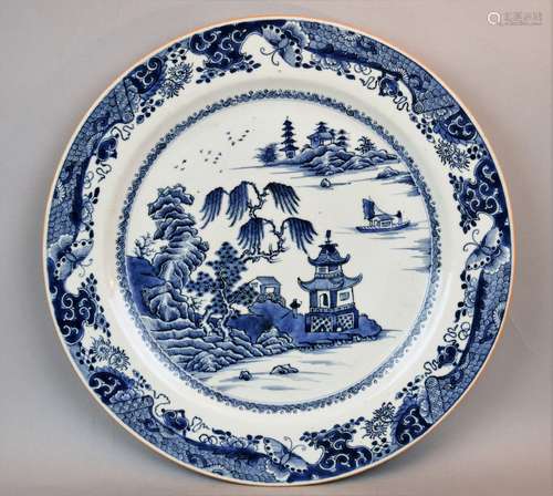 Porcelain charger. Chinese Export ware. 18th century. Underglaze blue decoration of pavilions in a landscape. Brocade and butterfly borders. (hairline). 14-1/2