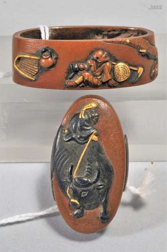 Set Fuchi-Kashira, Japan. 18th/19th century. Copper with mixed metal inlay of gold and shakudo. Decoration of a water buffalo and farmers. Signed and with a kakihan.