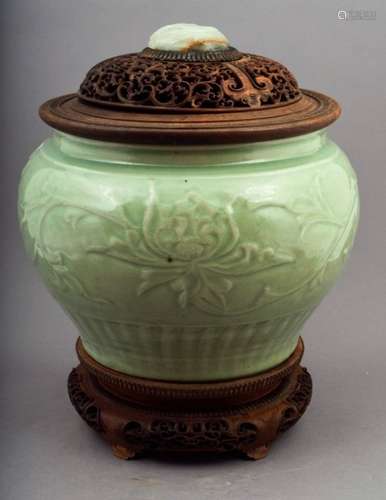 Celadon jar. China. Early Ming period. 15th century. Molded decoration of lotus scrolls with petals at the base. Sea-green Celadon colour. Mounted as an incense burner with a carved and fitted rosewood stand and cover. Cover inset with a white jade carved with lotuses. jar- 12