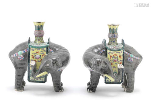 A pair of famille rose models of caparisoned elephants supporting vases