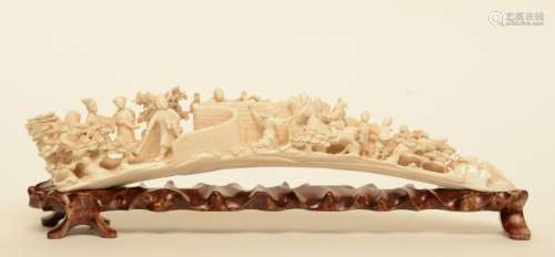 An ivory tusk carved with animated scenes, on a matching wooden base, first half of 20thC, L 45,5 cm - Weight 1.046 g