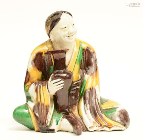 A Chinese Sansai sculpture depicting a seated figure holding a vase, Kangxi, 18thC