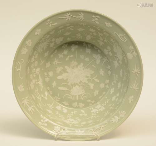 A Chinese celadon ground bowl, relief moulded with floral motifs, 19thC, H 12,5 - Diameter 41 cm (firing faults)