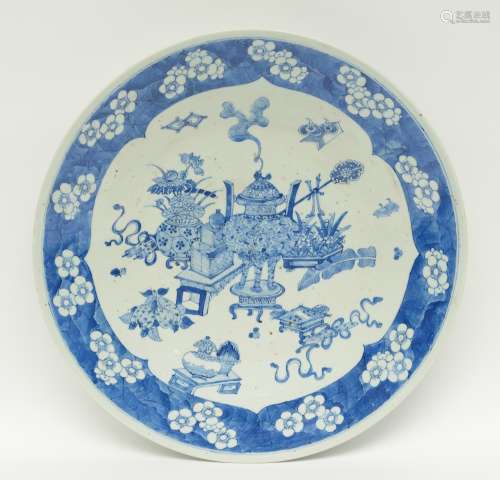 A Chinese blue and white plate decorated with antiquities and prunus blossoms, 19thC, H 7,5 - Diameter 47 cm (chip on the rim)