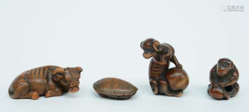 Three Japanese wooden katabori netsuke, one depicting a buffalo at rest, one a monkey playing with a peach kernel and one a lurking turtle; added a ditto okimono depicting a dog playing with a ball; W 6,2 - 5,3  - 3,9 - 2,7 cm