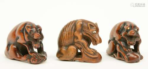 Three Japanese wooden katabori netsuke depicting wolves defending their prey, early Meiji-period, two of them signed, W 4,8 - 4,3 - 4,1 cm