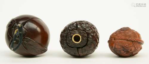Two Japanese wooden karakuri netsuke, one in the form of a peach with inside two Go-playing man; the other one in the form of a lychee with inside two figures with a broom; added a finely basso relievo carved wooden katabori netsuke in the form of a peach kernel, the lot early Meiji-period, signed, W 4,1 - 3,6 - 3,1 cm