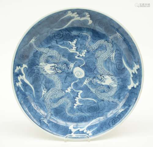 A Chinese blue and white plate decorated with dragons and the flaming pearl, 19thC, H 5,5 - Diameter 34,5 cm (chips on the rim)
