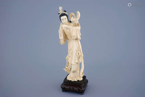 A Chinese carved ivory figure of Guanyin with a bird on wooden base, 19th C.