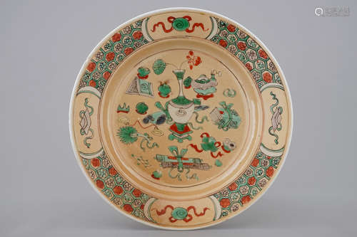 A Chinese famille verte café au lait ground plate with precious objects, Kangxi