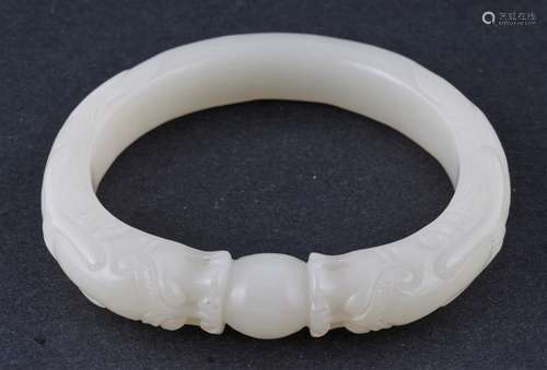 Jade bracelet. China. 18th century. Litchee white stone. Carved with two dragon heads confronting on a celestial pearl.