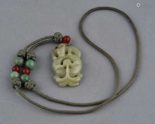 Jade pendant. China. 19th century. Celadon coloured stone. Carving of a swirling dragon.