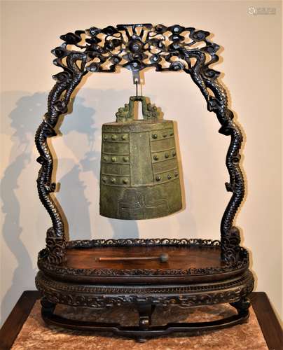 Archaic style bronze bell. China. 19th century. Chung with archaic scrolling and kuei dragons. Rosewood stand carved with dragons and a floral pierced gallery. 26