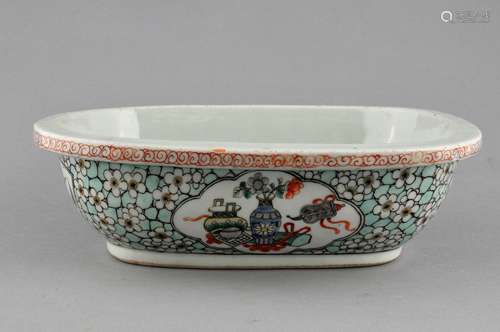 Porcelain planter. China. 19th century. Rounded corner rectangular form. Famille Verte decoration of reserves of The Hundred Antiques and flowers of prunus strewn 