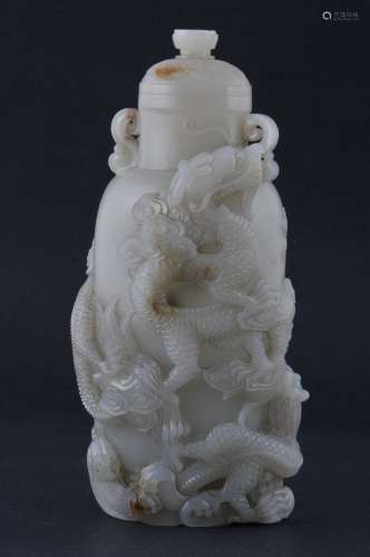 Jade covered jar. China. Late 19th century. Stone of a grey-white colour with russet veins. Surface carved in high relief with dragons and clouds. 7
