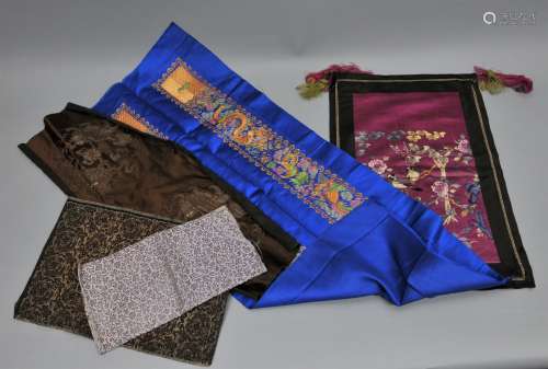 Lot of six silk textiles: Two sleeve bands mounted on one blue panel. Panel of purple silk embroidered with flower, a panel with foo dogs and two pieces of brocade.