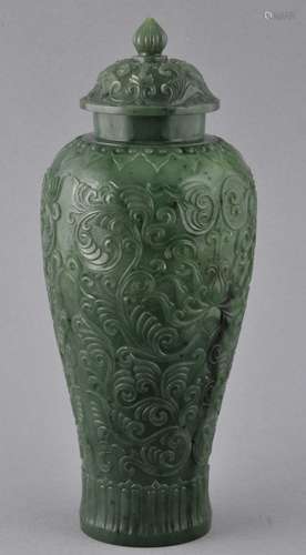 Jade covered jar. China. 20th century. Highly translucent green stone. Surface carved with a stylized lotus scrolling in low relief. Ch'ien Lung mark in the gold on the base.  8-1/2