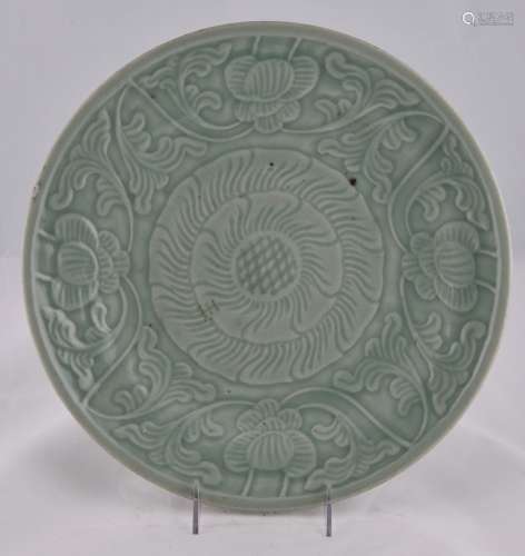 Porcelain plate. China. 19th century. Surface carved with flowers beneath a pale celadon glaze. 14