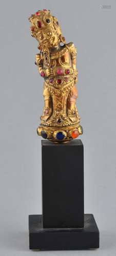 Dagger hilt. Bali. 20th century. Kris hilt of gilt metal set with glass and various semi-precious stones in repousse in the shape of Raksha. 5-1/2