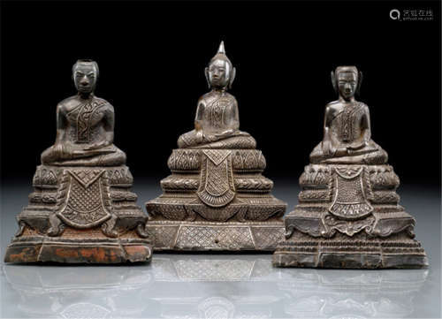 THREE LOW-ALLOY SILVER SHEATH FIGURES OF BUDDHA SHAKYAMUNI, Thailand, Rathanakosin period, one dated 1928, both others late 19th Ct. to early 20th Ct., all three silver sheath Buddha's modelled around a clay core and seated in sattvasana on a tiered throne, their right hands in bhumisparshamudra while the left ones rest on their laps, wearing samghati and their faces displaying serene expressions, each reverse with incised inscription - Property from a European private collection, acquired prior 2007 - Partly small damages due to age, wear