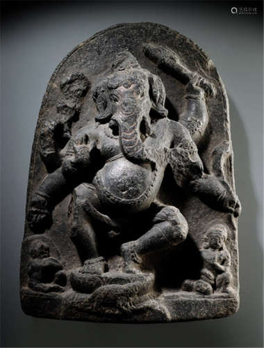 A BLACK STONE STELE DEPICTING GANESHA, North-East India, Pala Period, 11th/12th Ct., Ganesha is sculptured in dancing posture on a lotus base carved with his vehicle the rat to the front, his six arms radiating around his body, some damaged, others holding the prescribed attributes, wearing dhoti, bejewelled, pot-bellied and his elephant-head with curling trunk - Property from an old Bavarian private collection, acquired between 1960 and 1990