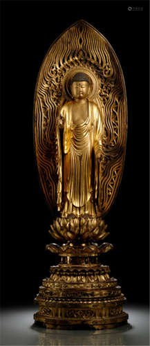 A GILT- AND BLACK-LACQUERED WOOD FIGURE OF BUDDHA, Japan, late Edo period, standing in samabhanga on a separate carved lotus base placed on a tiered throne, both hands in vitarkamudra, wearing monk's garment falling down in stylized pleats, his face displaying a serene expression with downcast eyes below arched eyebrows, urna, black painted moustache and a mandorla behind - Property from a French private collection, purchased from Lavoisserie - Gueilhers, La Rochelle, Frankreich, am 22.10.06 - Slightly rest.