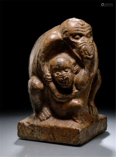 A STONE SCULPTURE OF A MONKEY HOLDING ITS YOUNG