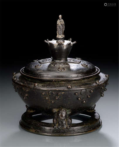 A RARE BRONZE KORO, Japan, probably Kamakura period, tripod koro with stands in the shape of three seated shishi on a round foot rim. The cover with six holes and a lotus-shaped knob on a base with four 'mitsutomoe' crests with a figure of standing Buddha Amida - Property from an old Austrian private collection - Some wear due to age