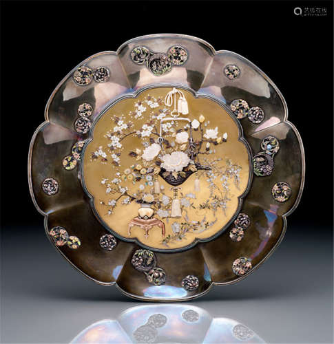 A FINE SILVER SHIBAYAMA DISH, Japan, Meiji period, lobed dish with floral shape, the central gold lacquered roundel is decorated with a vase on a stand and a hanging basket containing various floral sprays like wisteria, lilies, peonies und chrysanthemums, details inlaid in ivory, mother-of-pearl and horn - Minor wear