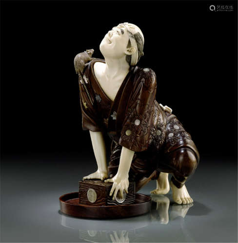 A WOOD AND IVORY OKIMONO OF A RATCATCHER, Japan, signed Miyao, Meiji period, carved on his knees, holding a box with both hands that assumably contains rats. His finely carved face features show despair while a rat is running across his shoulder. Details inlaid in ivory and mother-of-pearl - Minor wear, tiny chips, tail of rat rest., partly fine hairline cracks