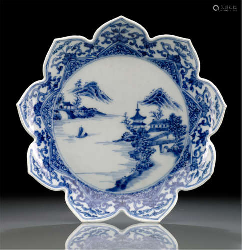 A LOTUS-SHAPED PORCELAIN DISH, Japan, Arita, 18th Ct., lobed form, decorated in underglaze blue with a roundel enclosing a sea scape with pagodas, reserved with foliage and floral patterns - Partly small firing cracks, one chip to the rim