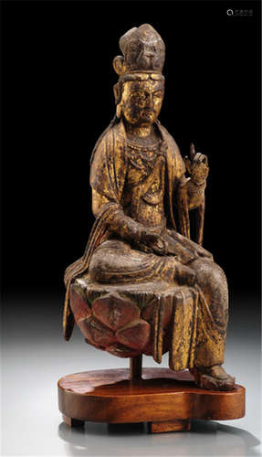 A FINE AND RARE GILT-LACQUERED AND POLYCHROME FIGURE OF GUANYIN, China or Korea, Song/early Ming dynasty. Seated in lalitasana on a lotus base with both hands in a form of vitarkamudra, wearing a dhoti, cape draped over both shoulders, bejewelled, his face with downcast eyes, the hair combed in a chignon and secured with a tiara carved to the front with a character - Property from an old German private collection, by descent in the 1960'ies from a family member to the present owner - Minor damages due to age, wear