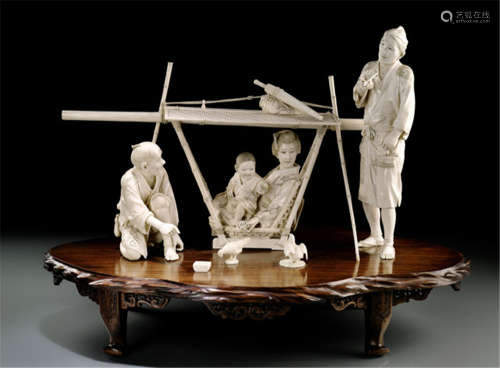 A FINE CARVED GROUP OF IVORY FIGURES DEPICTING A SCENERY OF RESTING CARRIERS AND A LADY IN A PALANQUIN, Japan, Meiji period - Lively and naturalist work, the group consisting of two carriers, an elegant lady with child in a sedan chair and two chicken with bowl, placed on a fine wooden stand with ornate carvings - Very few age cracks, slightly rest., otherwise good condition