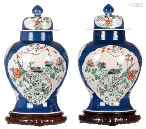 A pair of Chinese bleu poudré vases and covers, the roundels famille verte, decorated with birds and flower branches, with a Kangxi mark, on a matching wooden base, H 45,5 cm