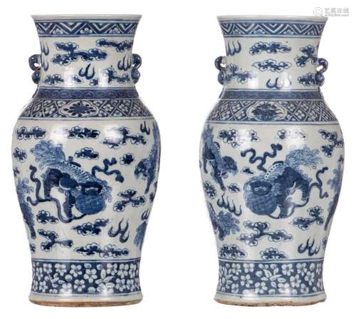 A pair of Chinese blue and white vases, decorated with Fu lions, 19thC, H 35,5 cm (crack)