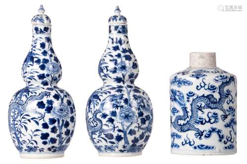 A pair of Chinese blue and white double gourd vases and covers, decorated with dragons and flower branches, marked Kangxi, H 26 cm (damage); added a blue and white cylindrical tea caddy, decorated with dragons and a flaming pearl, H 17,7 cm