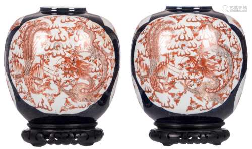 A pair of Chinese blue ground and gilt decorated vases, the roundels iron red with dragons, phoenixes and flaming pearls, 19thC, (on matching wooden stands), H 24 cm (with stands)