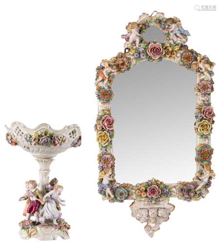 A polychrome decorated Saxony porcelain wall mirror, 46 x 83 cm (candle holders missing); added a ditto centerpiece worn by a group of children, H 39 cm (some damage)