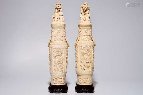 A pair of tall Chinese ivory vases and covers on wooden base, early 20th C.