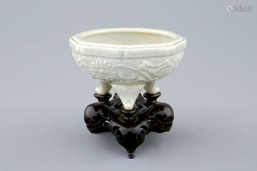 An octagonal Chinese celadon tripod censer on carved wooden base, impressed Qianlong mark, 19th C.