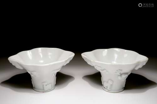 A pair of blanc de Chine relief decorated libation cups, Kangxi