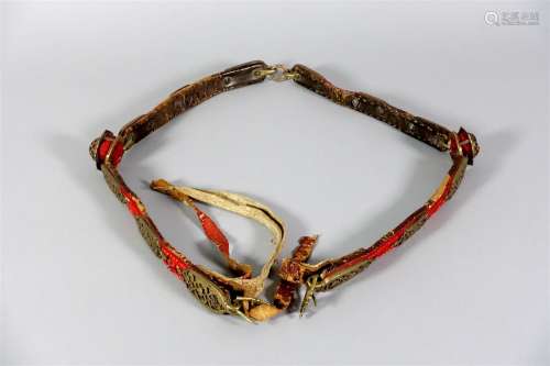 Sangle de cheval Ottomane. Plaques décoratives en bronze ajouré de palmettes et fleurons, appliquées sur des lanières de cuir et feutre rouge, réunies par deux cabochons et anneaux.
