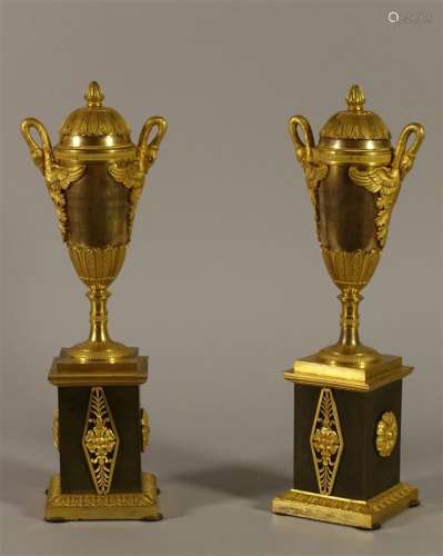 Paire de vases-flambeaux en bronze doré, les anses en forme de cygnes aux ailes déployées. Ils reposent sur un piédouche et une base à décor de palmettes. La partie supérieure se retourne pour former un binet.