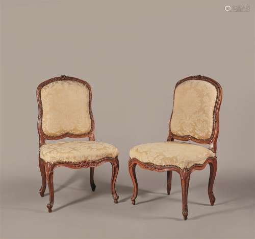 Paire de chaises à dossier plat violonné en bois naturel mouluré et sculpté de fleurettes et feuillages, les pieds cambrés.