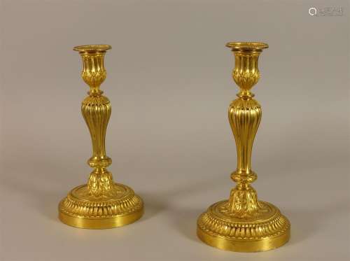Paire de bougeoirs en bronze doré et ciselé, le fût de forme balustre cannelé à décor de lauriers tressés, feuilles d'acanthes et frises de perles.