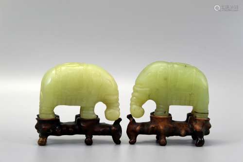 Two Chinese carved jade elephants on wood stands.