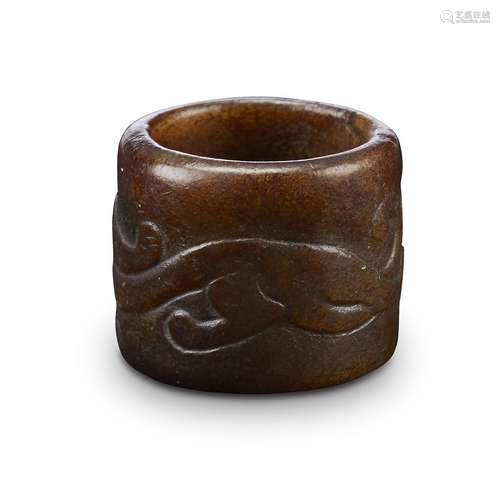 A Chinese brown jade ring, carved with a sinuous qilong, possibly ming dynasty