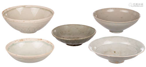 Four Chinese qing bai bowls of the Southern Song type, one with carved lotus decoration on the outside, H 6,7 - ø 17,8 cm; added a Chinese yaozhou type bowl with lotus shaped relief on the outside, H 4,4 - ø 14,2 cm